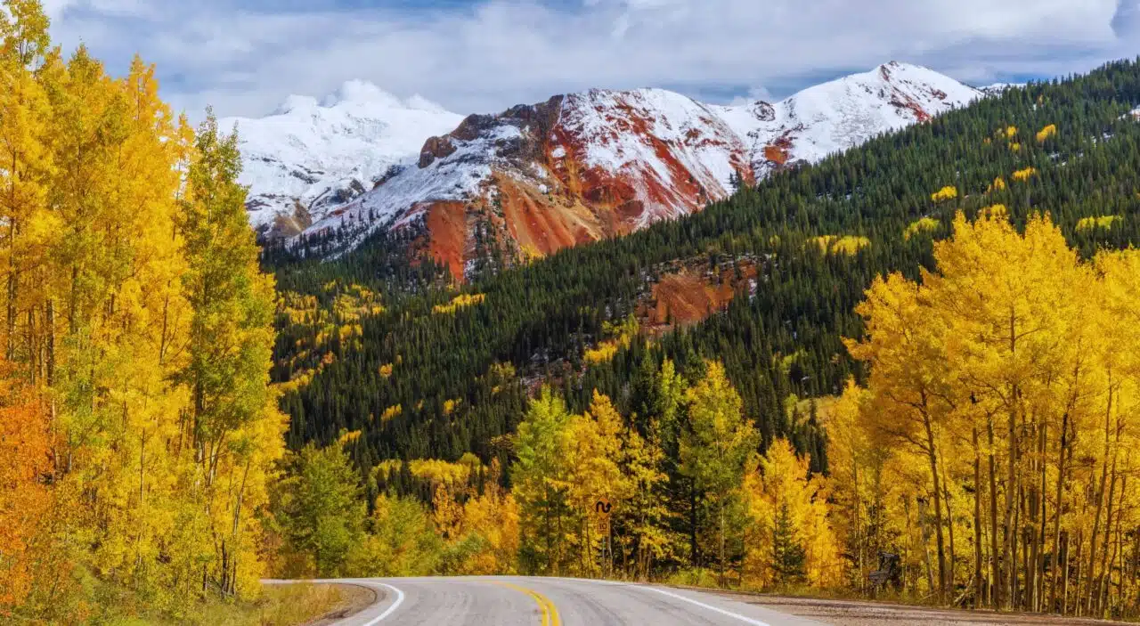 autumn trees and red mountain on the million dollar highway fall road trip