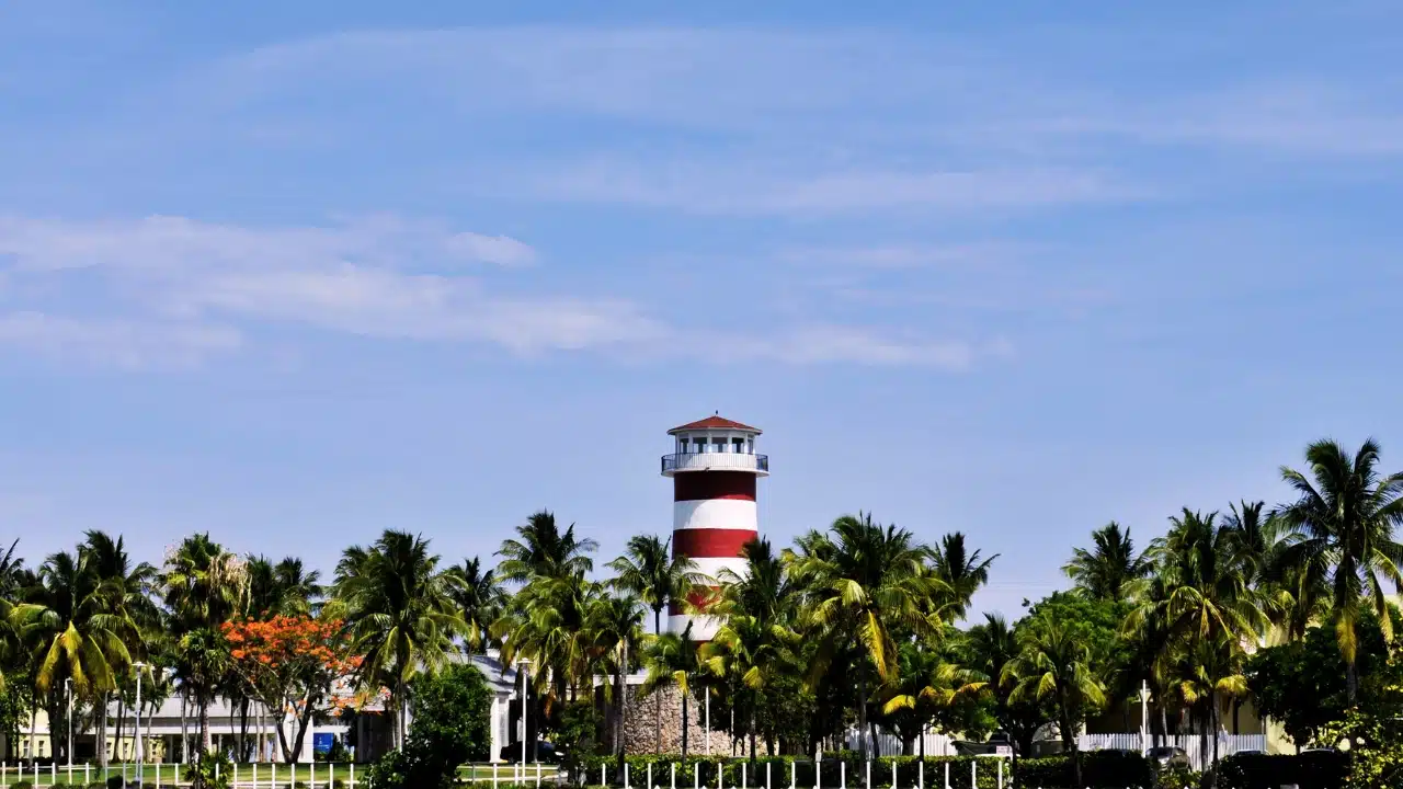 Red and white lighthouse surrounded by palm trees in Freeport, Grand Bahama, The Bahamas, showcasing the tropical beauty and coastal charm of this popular Caribbean destination.