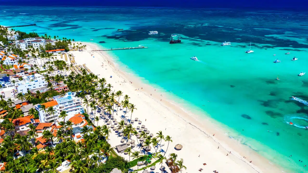 Aerial view of Punta Cana, Dominican Republic, featuring white-sand beaches, turquoise Caribbean waters, luxury beachfront resorts, and palm trees along one of the Caribbean's most popular tropical vacation destinations.