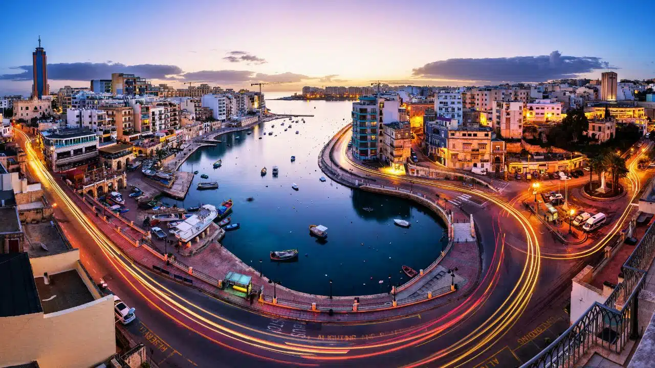 Scenic view of Valletta, Malta, at sunset showcasing the Grand Harbour, historic waterfront, colorful city lights, and Mediterranean architecture, highlighting one of Malta's top travel destinations.