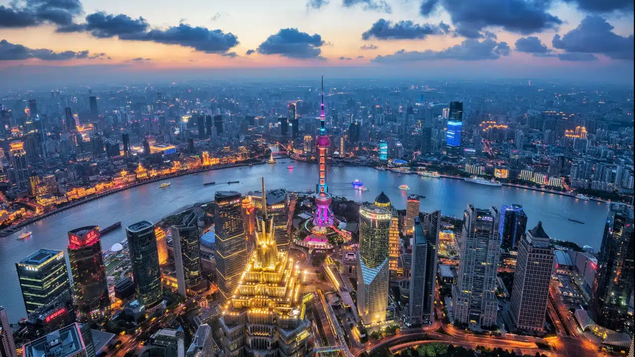 Aerial panorama of Shanghai, China, highlighting the iconic Oriental Pearl Tower, Lujiazui skyline, Huangpu River, and vibrant city lights, one of Asia's top travel destinations.