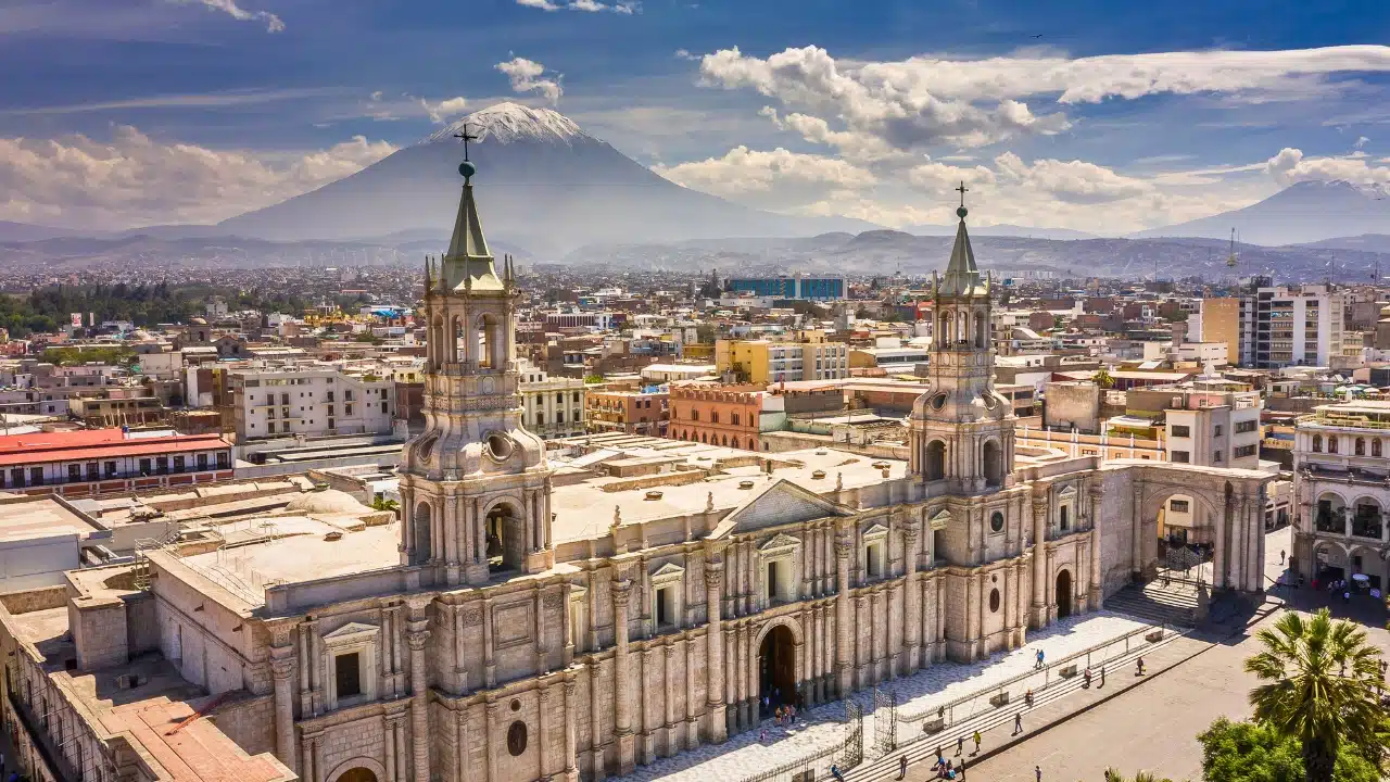 Scenic view of Arequipa, Peru, with the historic Arequipa Cathedral in the foreground and snow-capped Misti Volcano in the background overlooking the city.