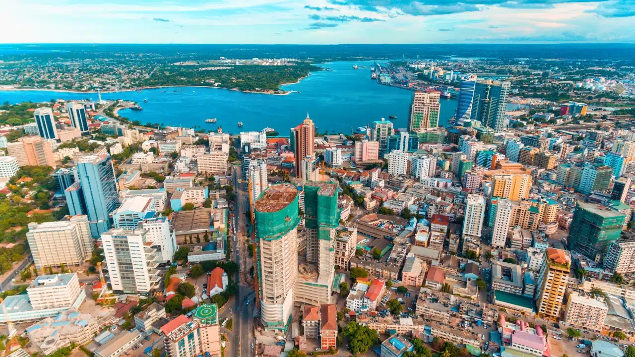 Aerial view of Dar es Salaam, Tanzania, showing the city skyline, bustling urban center, and expansive harbor along the Indian Ocean.